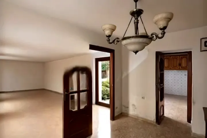 Estancia vacía de una casa antigua, con puertas de cuarterones y salida a un patio