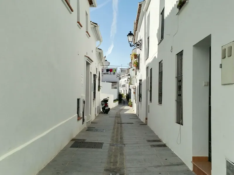 Calle estrecha de casco antiguo andaluz con fachadas encaladas